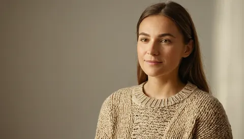 Woman in beige knit sweater looking at camera with soft expression